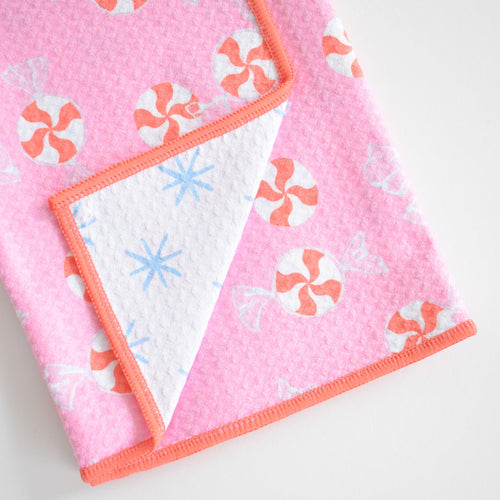 Sara Fitz Anywhere Towel, Peppermint, patterned with red and white peppermint candies, showing an absorbent fabric underside with blue starbursts.