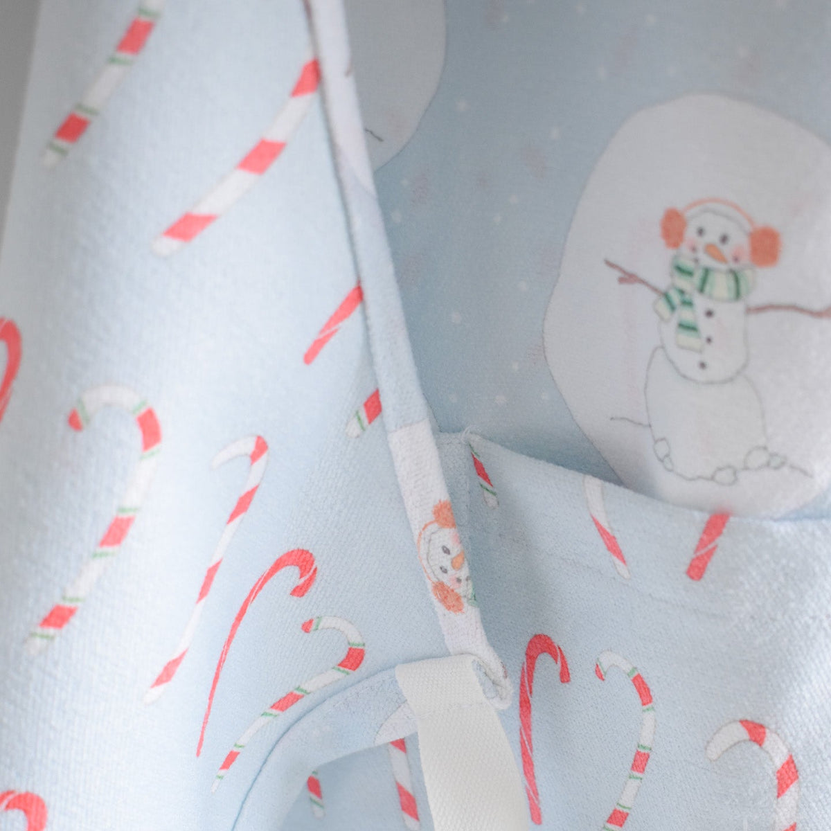 Attach + Go Apron, Happy Snowman in light blue fabric with a pattern of candy canes and snowmen wearing earmuffs.