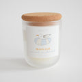 The Sara Fitz Beach Club Candle is a 10 oz frosted glass coconut soy wax candle with a cork lid, featuring a seagull on a striped float label. Scented with sea coconut & sea salted shells. Hand-poured in Maine for that beachy aroma.