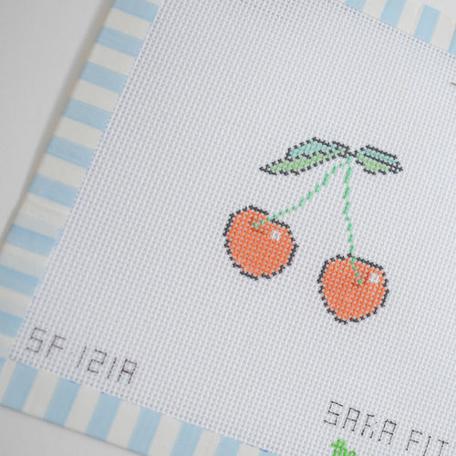 The MINI Cherries Needlepoint by Sara Fitz features two red cherries with green stems and leaves on white, bordered by blue and white stripes. Faint stitched text appears at the bottom. Ideal for 18 mesh stitching.