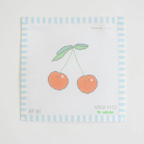 The Sara Fitz Cherry Needlepoint is a stitch-painted 18 mesh canvas featuring two red cherries with green leaves and a blue and white striped border. Includes an attached needle for easy stitching.