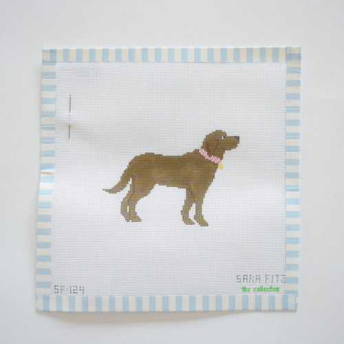 The Chocolate Pup Needlepoint by Sara Fitz is an 18 mesh canvas featuring a brown dog with a pink collar, centered on white fabric with blue and white striped borders and includes a needle attached to the upper left corner.