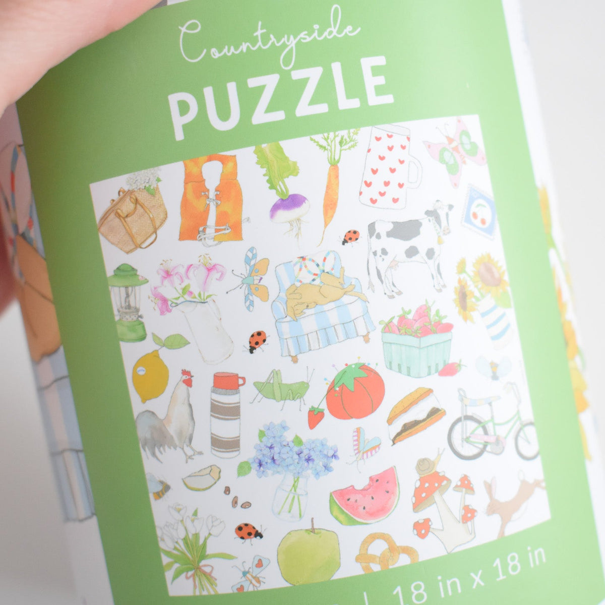 Packaging for the 500-piece Countryside Puzzle, featuring a vintage collage of colorful illustrations including a cow, bicycle, watermelon, flowers, and garden items.