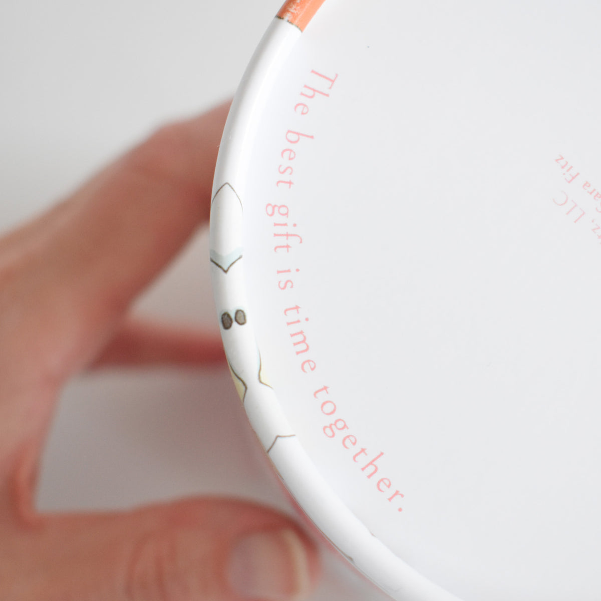 A hand holds a white cylindrical 500-piece Holiday Puzzle container with the text, The best gift is time together, printed along the rim.