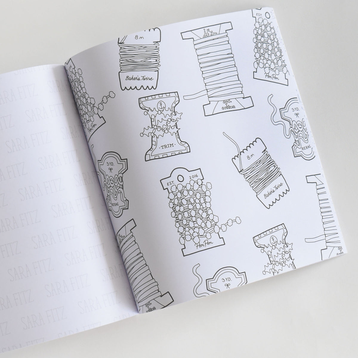 Open Coloring Book Holiday featuring Sara Fitz illustrations of black-and-white line art with spools of ribbon, bakers twine, trim, and pom-poms.