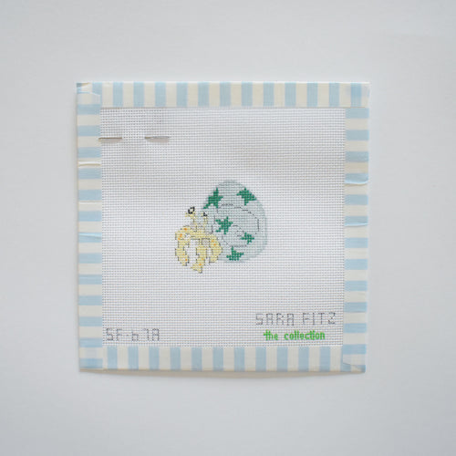 A stitch-painted MINI Star Hermit Crab Needlepoint by Sara Fitz is shown on white fabric with blue stripes, featuring a small hermit crab. Text at the bottom reads “Sara Fitz” and “MINI Star Hermit Crab Needlepoint.”.