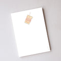 Holiday Trimmings Notepad, a rectangular, unlined notepad featuring a small illustration of a spool of red bakers twine at the top center.