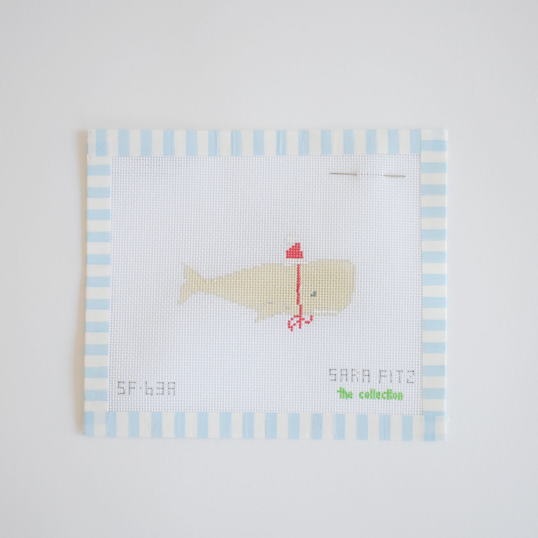 The Santa Whale Needlepoint by Sara Fitz features a beige whale in a red party hat and bowtie on 18 mesh canvas, bordered by blue and white stripes.