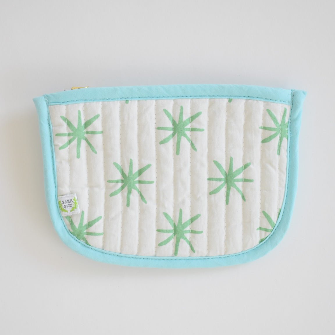 The Coin Pouch, Green Star by Sara Fitz is a cotton quilted pouch with a light blue border and zipper, white background with green starburst patterns, and a small side label. Made in India—ideal as a stylish card holder.