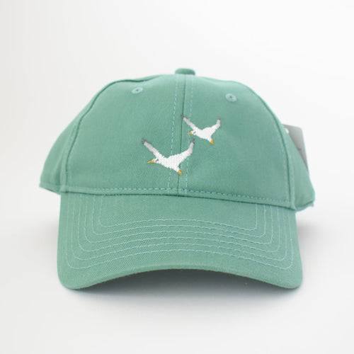 The Sara Fitz Seagull Hat, Moss is a green cotton baseball cap with two white seagulls embroidered on the front and an adjustable back strap, shown against a plain white background.
