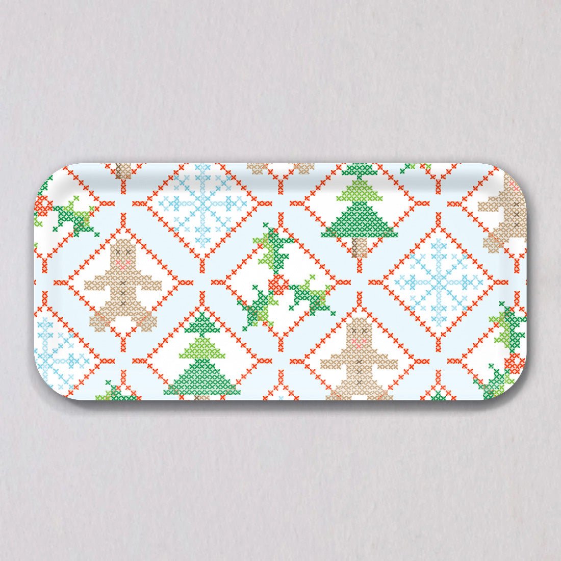 Sara Fitz Small Holiday Cross Stitch Tray made of melamine-coated birch wood, featuring a repeating pattern of gingerbread men, pine trees, snowflakes, and holly sprigs framed by red diamond borders.