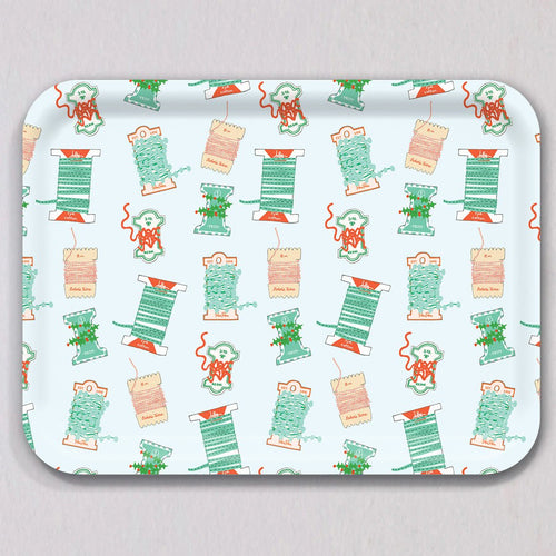 Large Holiday Trimmings Tray by Sara Fitz: a rectangular melamine-coated birch wood tray featuring a repeating pattern of colorful spools of holiday ribbon and twine.