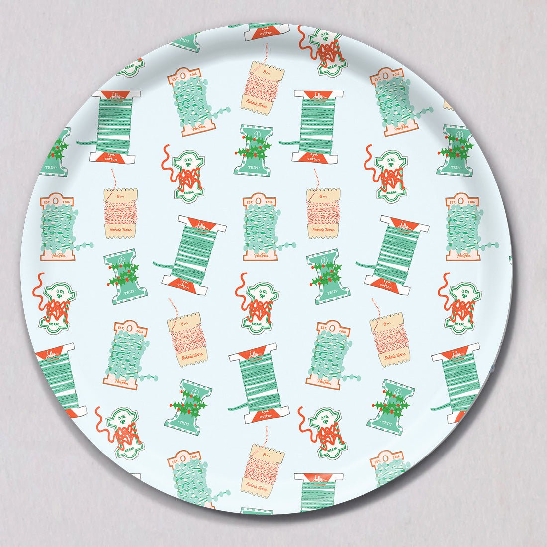 Large Holiday Trimmings Tray, Round, a melamine-coated birch wood tray with a repeating pattern of colorful spools of ribbon and holiday trim.