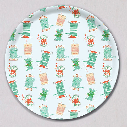 Large Holiday Trimmings Tray, Round, a melamine-coated birch wood tray with a repeating pattern of colorful spools of ribbon and holiday trim.