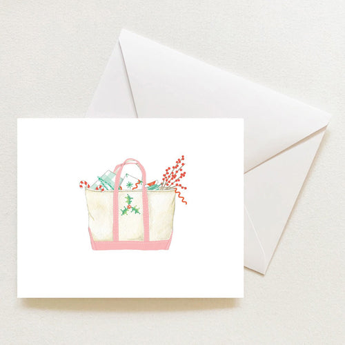 A Holiday Tote Note Card from Sara Fitz featuring a watercolor illustration of a canvas tote bag filled with holiday items, including candy canes and berries, shown with a matching envelope.