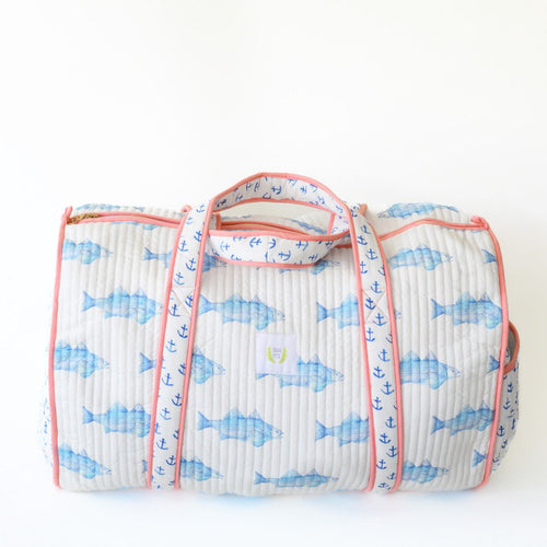 The Sara Fitz Weekender Tote, Blue Fish features quilted cotton with blue fish and anchor patterns, pink trim, and wraparound handles, shown on a plain white background.