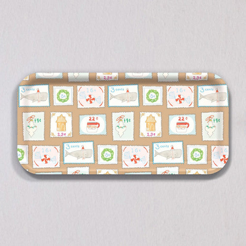 Sara Fitz Small Holiday Stamps Tray: a rectangular, melamine-coated tray patterned with vintage-style holiday postage stamps featuring illustrations of whales, gingerbread houses, wreaths, and candy.