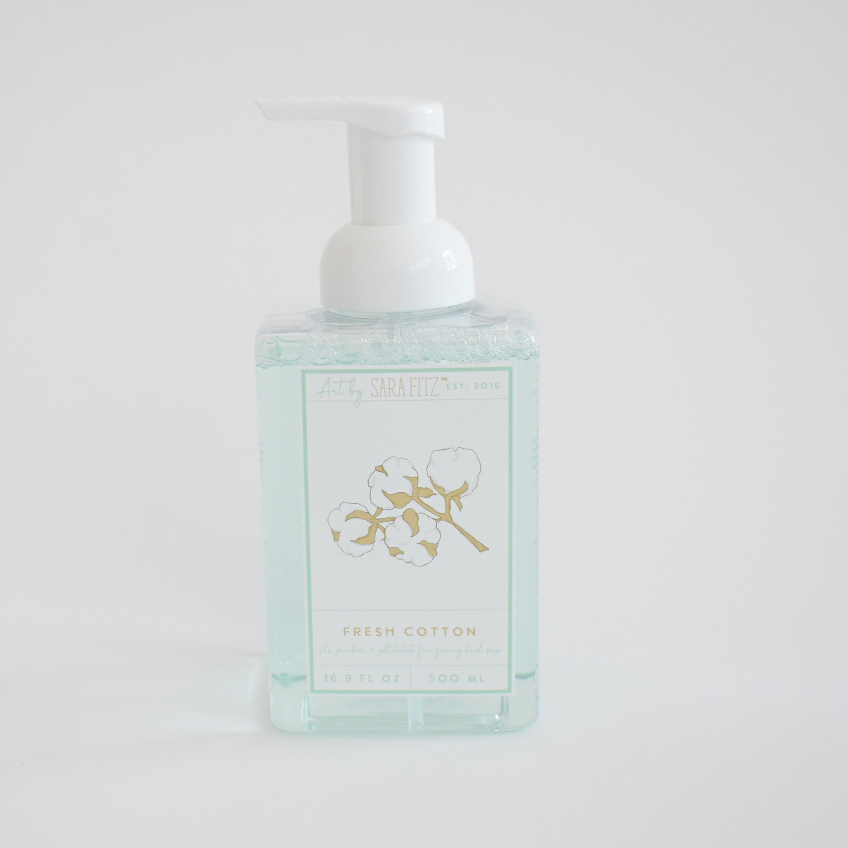 The Sara Fitz Foaming Soap Fresh Cotton comes in a clear pump bottle with a cotton plant illustration on white. This 300 ml non-toxic soap gently refreshes your hands with every use.