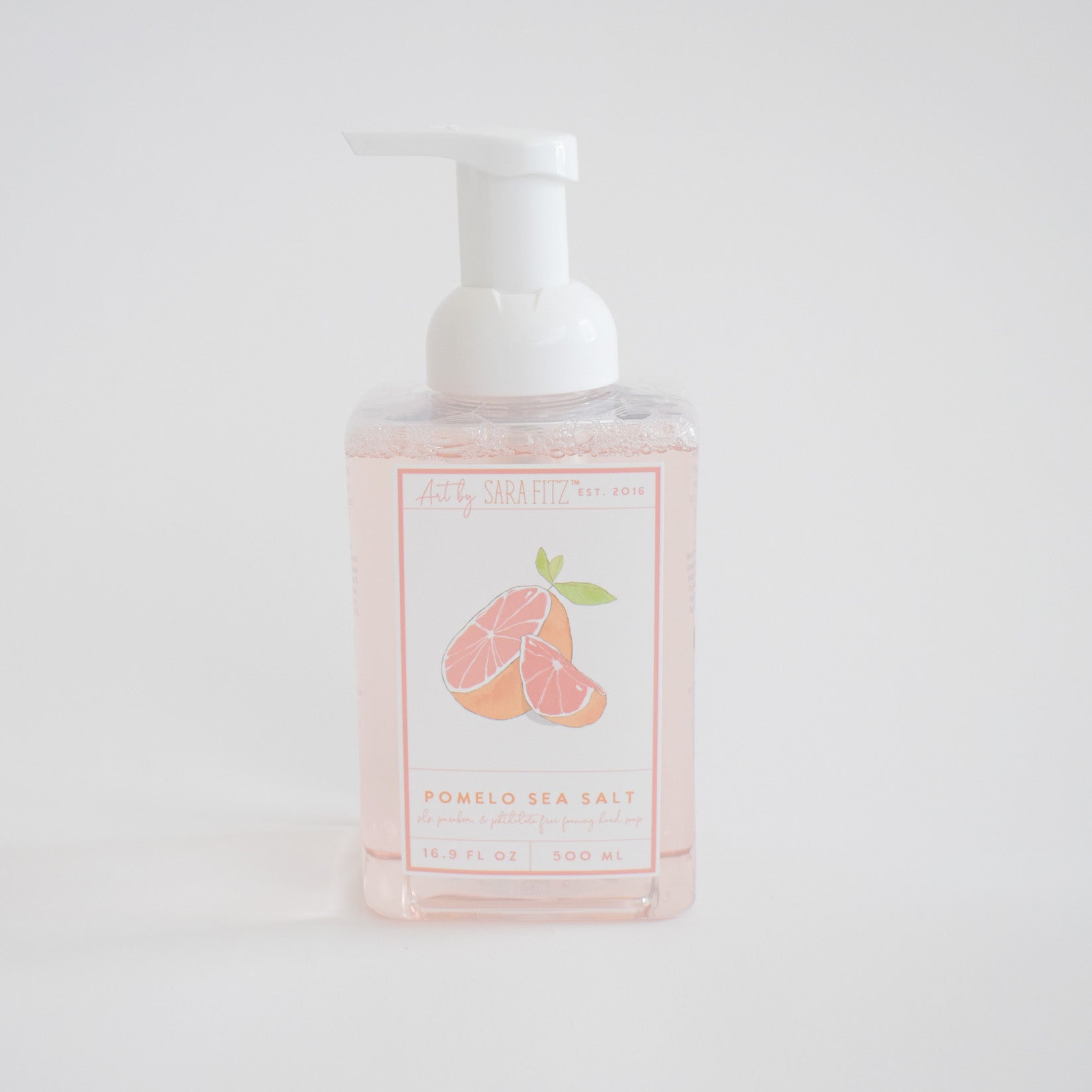 A clear pump bottle of Sara Fitz Foaming Soap Pomelo displays an illustration of sliced pomelo fruit on the label, set against a plain white background.