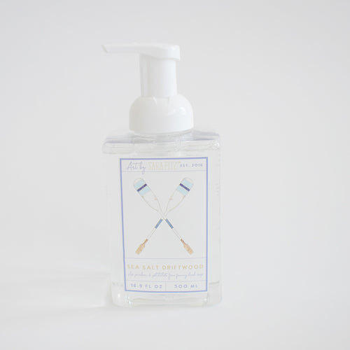 Sara Fitz Foaming Soap Oars comes in a clear 16.9 fl oz (500 ml) pump bottle labeled Sea Salt Driftwood, featuring non-toxic foaming soap and an illustration of two crossed blue and white oars on a white background.