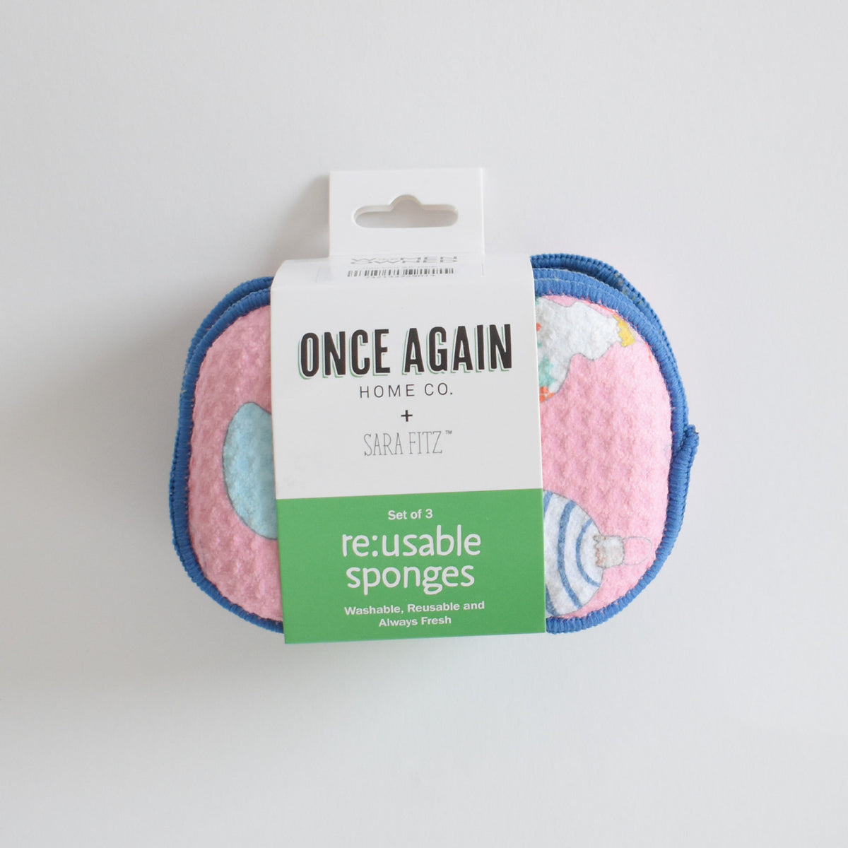 A set of three pink Re:usable Sponge, Ornament sponges with an ornament pattern, held together by a paper label that reads Once Again Home Co. + Sara Fitz.