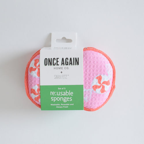 Two pink, circular, Re:usable Sponge, Peppermint sponges patterned with red and white peppermint candies, held together by a paper product label.
