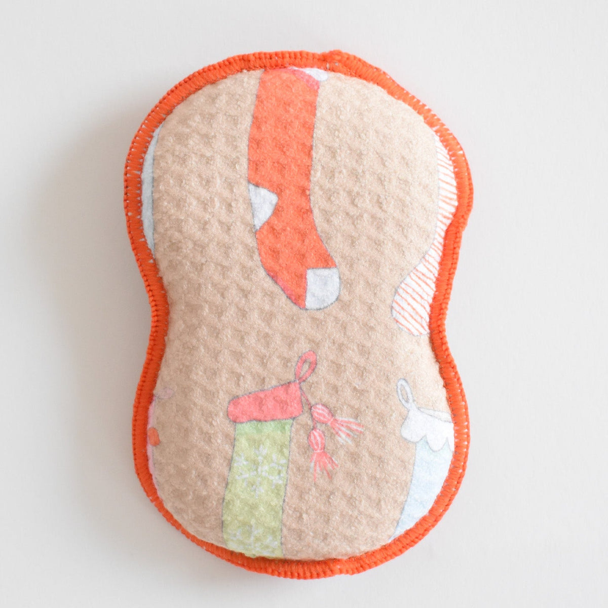 Hourglass-shaped, eco-friendly Re:usable Sponge, Stockings with an orange stitched edge and a tan background patterned with Christmas stockings.