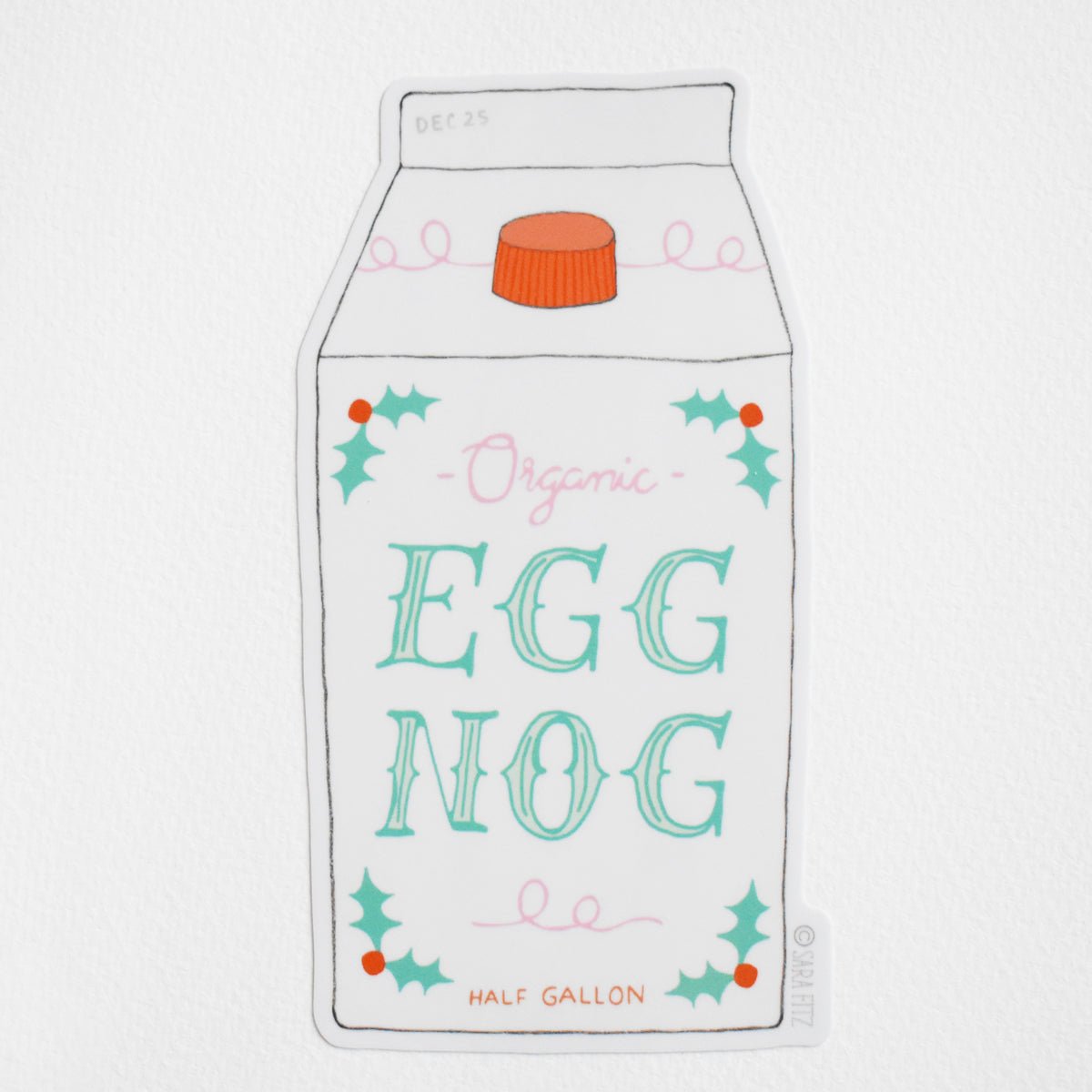 A Sara Fitz Eggnog Sticker featuring a weatherproof half-gallon carton of eggnog with an orange cap, decorated with holly sprigs and the text Organic EGG NOG and DEC 25.