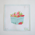 The Sara Fitz Strawberry Needlepoint features red strawberries with green leaves in a light blue basket on white fabric, bordered by blue and white stripes. An extra strawberry rests outside the basket on this charming 18 mesh canvas.