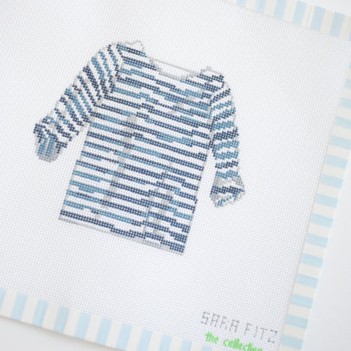 The Striped Shirt Needlepoint by Sara Fitz features a blue and white striped long-sleeve shirt on an 18 mesh stitch-painted canvas with a subtle blue striped border and "Sara Fitz" stitched in the lower right corner.
