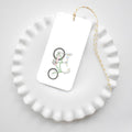 The Sara Fitz Banana Bike Tag features a green bicycle on white, tied with yellow and white baker’s twine. Resting on a scalloped ceramic plate, this charming tag makes any gift extra special for any occasion.
