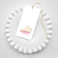 The Sara Fitz Conch Shell Tags, featuring a pink seashell design and yellow baker’s twine, are displayed on a white scalloped plate against a light background.