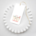 Sara Fitz Holiday Tote Tags: a rectangular gift tag featuring a watercolor illustration of a tote bag filled with holiday greenery, resting on a white fluted plate tied with yellow and white baker’s twine.
