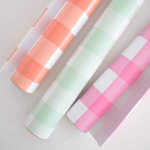 Four rolls of Sara Fitz Mint Check Gift Wrap featuring eco-friendly paper with large checkered patterns in pastel orange, green, and pink, arranged diagonally on a light background.