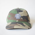 The Sara Fitz Striped Shirt Hat, Camo, is a cotton baseball cap with camo print, featuring a blue and white striped sweater embroidered on the front and an adjustable back strap. Shown on a plain white background.