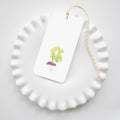A white scalloped plate displays a Sara Fitz Turnip Tag—rectangular with a turnip illustration—tied on with yellow and white baker’s twine for a charming packaging accent.